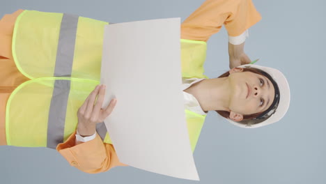 Vertical-video-of-Looking-up,-the-engineer-is-holding-her-hard-hat.