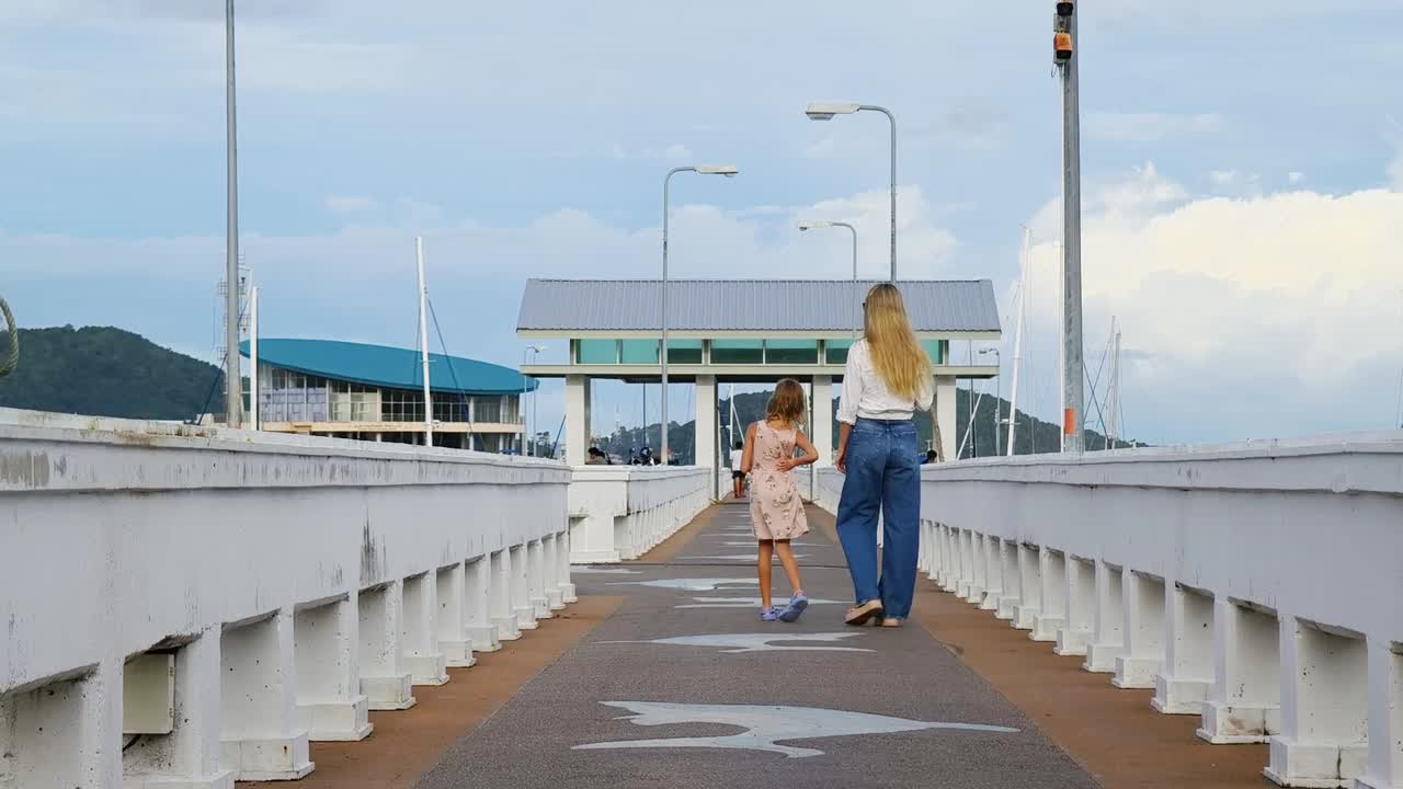 Mother and daughter walking on a pier