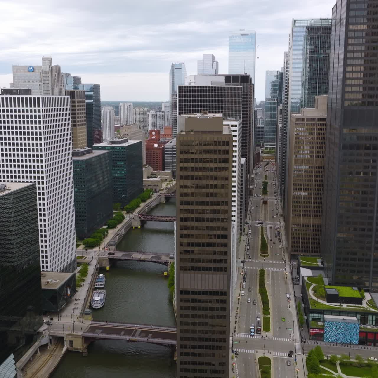 Chicago River with numerous bridges over. Drone rising along the beautiful buildings above the river. Grey day backdrop