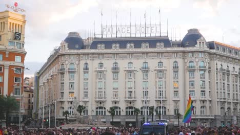 a vibrant pride protest outside the palace hotel in madrid, featuring colourful banners and enthusiastic lgbtq+ supporters.