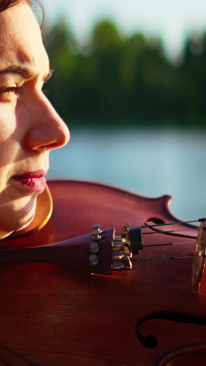 Young Woman Playing Violin Outdoors by the Lake