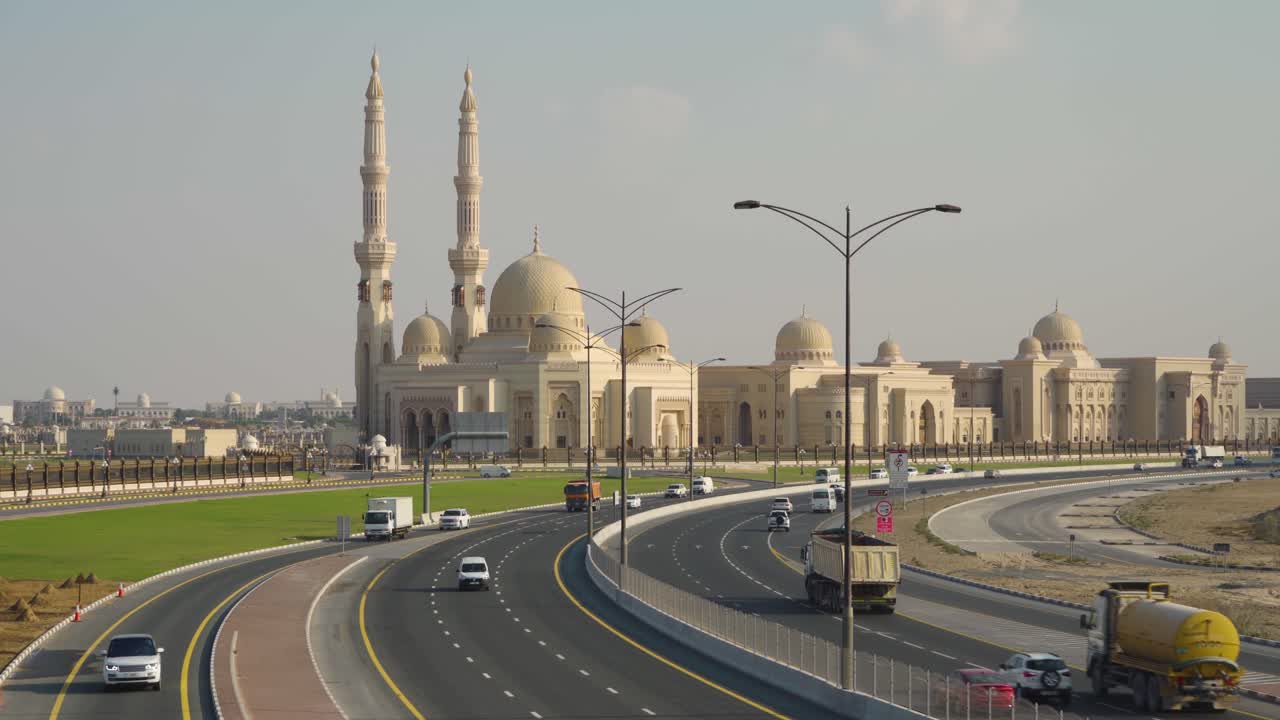 vista de la mezquita de la universidad al qasimia a lo largo de la vía urbana con diferentes vehículos que viajan durante el día en sharjah, emiratos árabes unidos