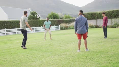 Fröhliche,-Vielfältige-Männliche-Freunde,-Die-An-Sonnigen-Tagen-Im-Garten-Fußball-Spielen