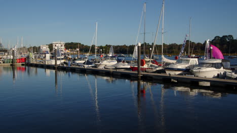 Beschleunigen-Sie-Die-Aufnahme-Mehrerer-Segeljollen,-Die-An-Festgemachten-Motoryachten-Vorbeisegeln-Und-Aus-Dem-Rahmen-Geraten,-Auf-Dem-Lymington-River