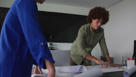 diverse male and female business colleagues in discussion at work looking at technical drawing