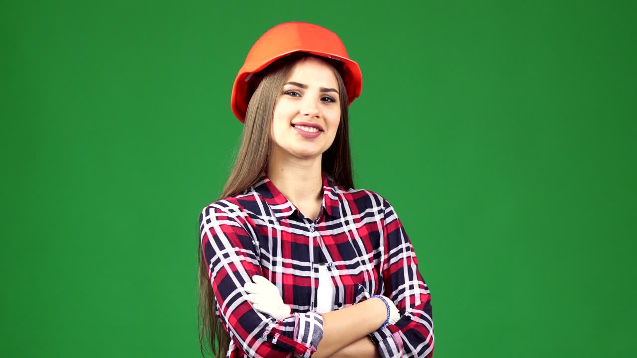 Gorgeous female construction worker in a hardhat smiling to the camera confidently