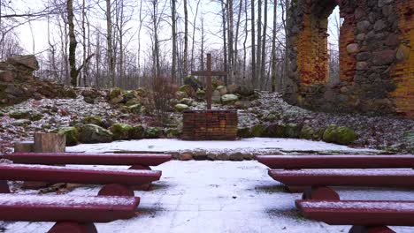 Walk-by-red-bench-and-approach-abandoned-church-cross,-boulder-wall-remains