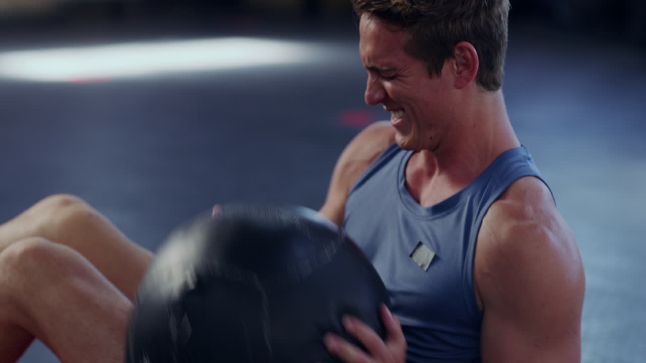 젊은 운동 선수 가 무게 가 있는 공 으로 운동 하고 있다