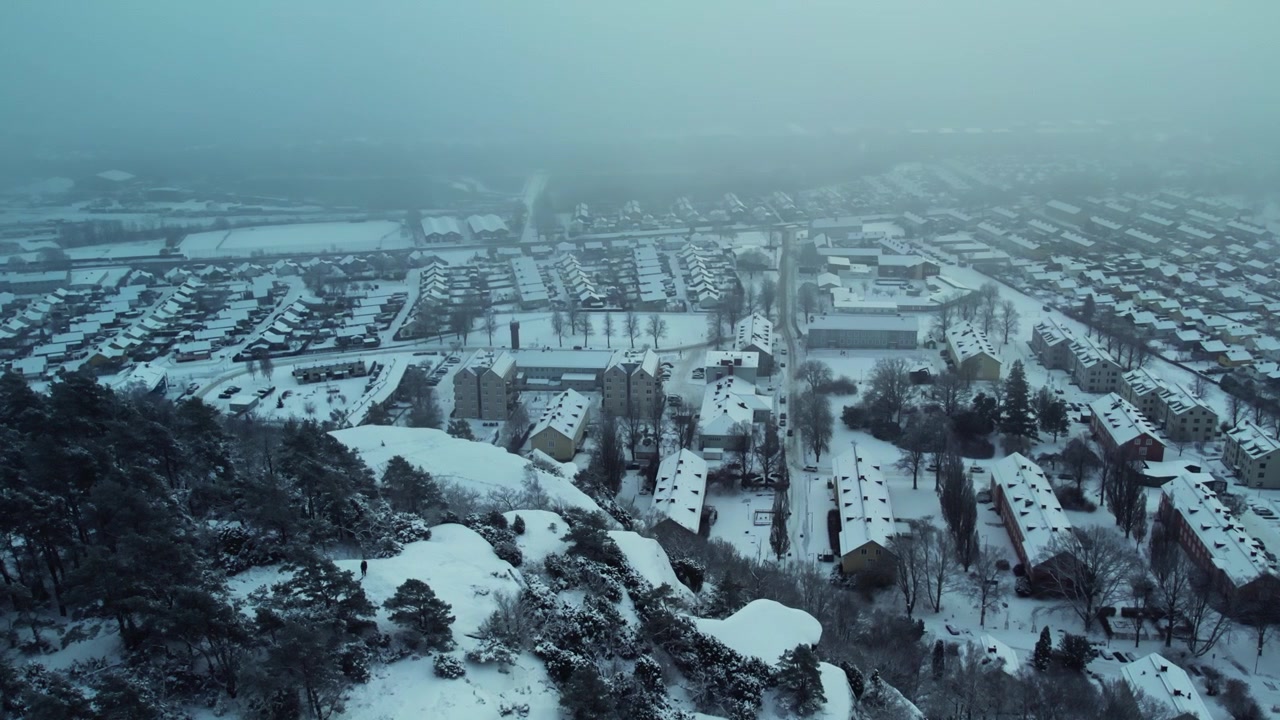 Karlı kış Gothenburg, İsveç'te, Utbyberget'ten Fjallbo ve Utby'ye bakan, tek tip apartman evlerinin bulunduğu bir uçurumun arkasından drone ile havadan çekilmiş görünüm.