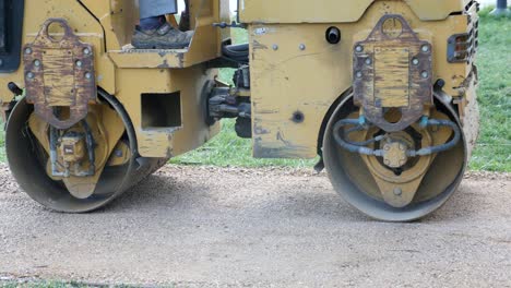 close-up of a yellow roller compactor working on a gravel road