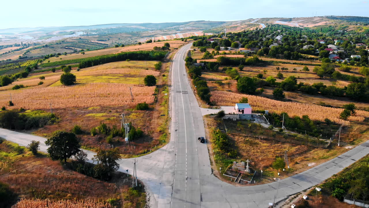 Aerial drone view of a crossroads without moving cars in highland. Small village and green hills on background. Sunny day. Balti, Moldova