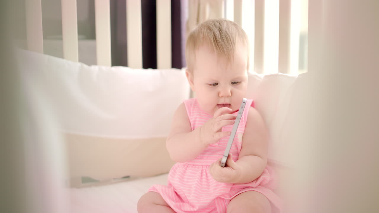 Baby girl holding smartphone in hands. Beautiful toddler girl with phone