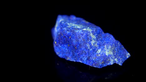 girando sin problemas un mineral azul (lapis lazuli) frente a un fondo negro