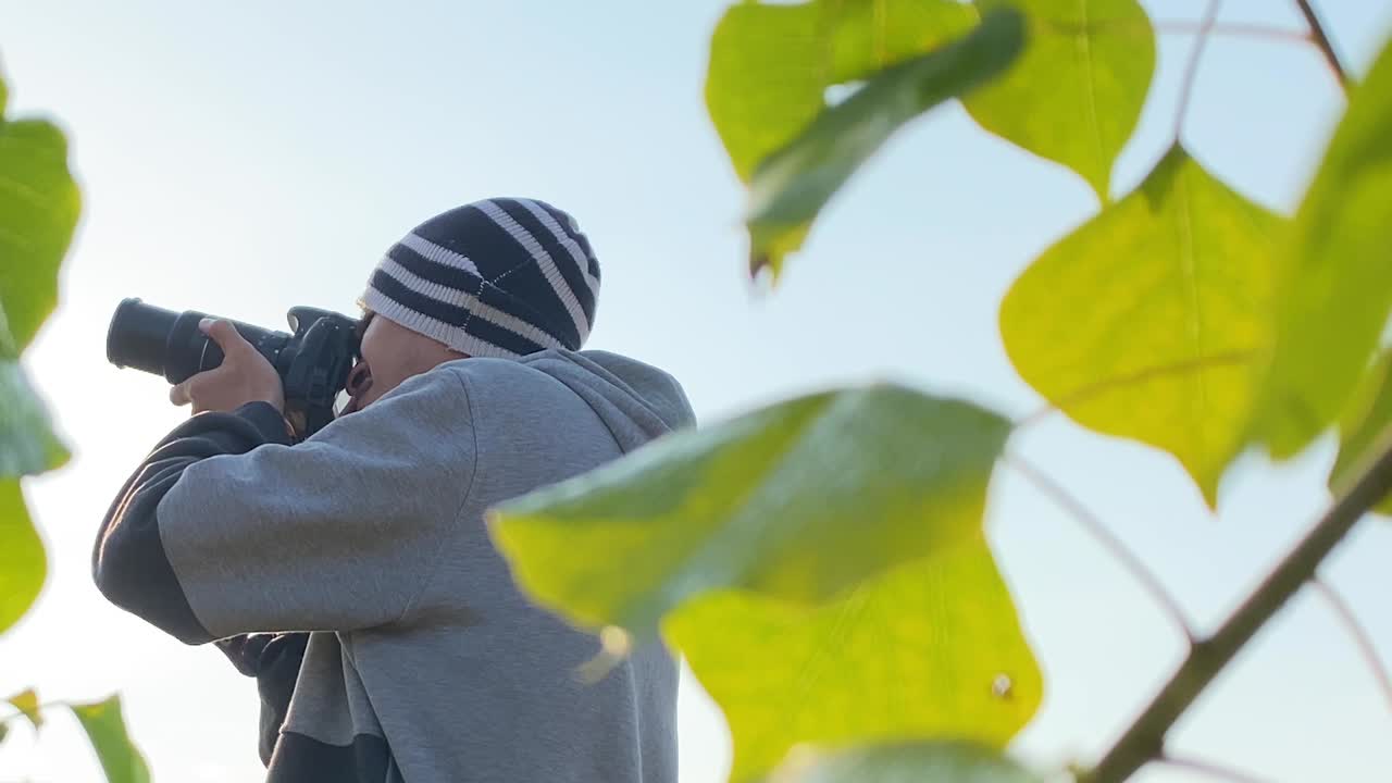 모자를 쓰고 있는 젊은 남자의 옆모습을 닫고 dslr 카메라로 사진을 찍는다