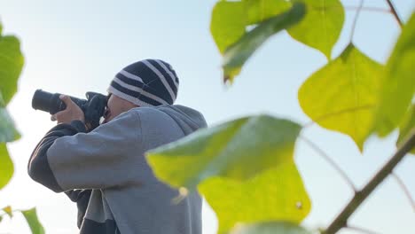 Close-up-side-portrait-of-young-man-wearing-hat-takes-pictures-with-DSLR-camera