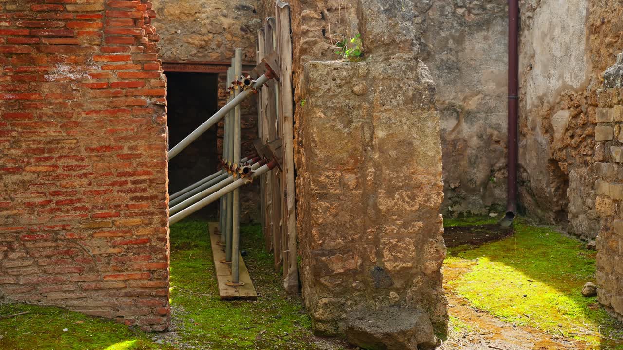 Verweerde muren en steunbalken in de ruïnes van Pompeii onthullen bewaard gebleven Romeins metselwerk, blootliggend baksteenwerk en voortdurende structurele conservering op een oude archeologische vindplaats