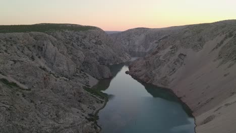 closeup of man watching zrmanja river above canyon at sunset, croatia