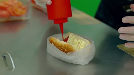 CU-Slow-motion-Cook-prepares-a-hot-dog-pours-it-with-red-sauce