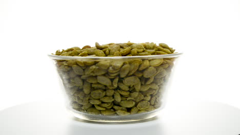 tazón de vidrio lleno de frijoles de soya conjunto giratorio contra fondo blanco de estudio aislado