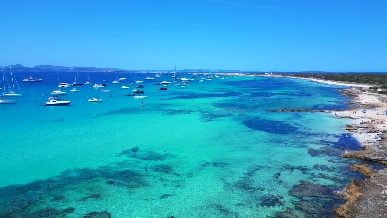Barche ancorate nelle splendide acque turchesi cristalline di Formentera, una spiaggia di sabbia bianca con Posidonia oceanica. Maestosa vista aerea ripresa da un drone in discesa