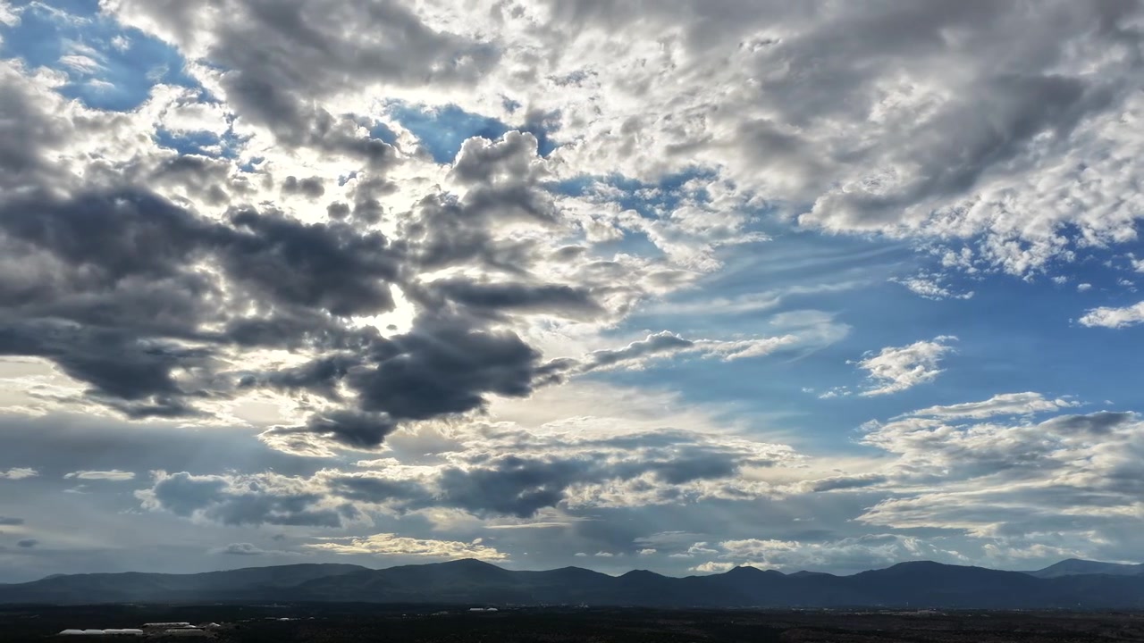 Timelapse aereo 4K che evidenzia i mutevoli modelli meteorologici su un vasto paesaggio del sud-ovest. Nuvole temporalesche pesanti e multistrato si formano rapidamente attraverso un cielo blu intenso sopra una mesa scura