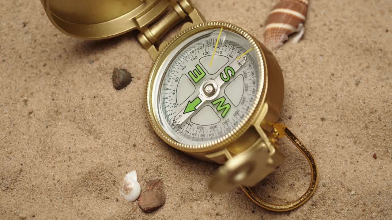 Gold compass on sand background close-up, focusing of golden compass. Traveling and tourism concept, navigation