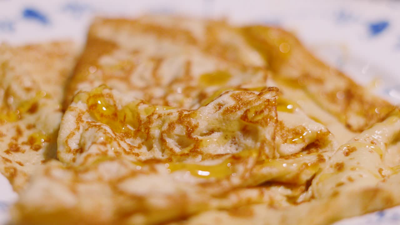 Golden Syrup Being Drizzled Over Freshly Cooked Delicious Pancake on Plate. Traditional British Dessert or Breakfast.