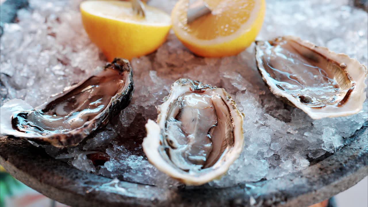 Close up of a bucket with raw oyster with lemons on ice at a restaurant