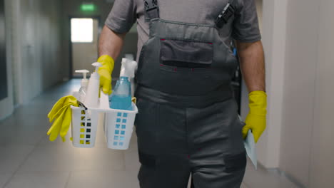 close up view of cleaning man hands carrying cleaning products while walking inside an office building