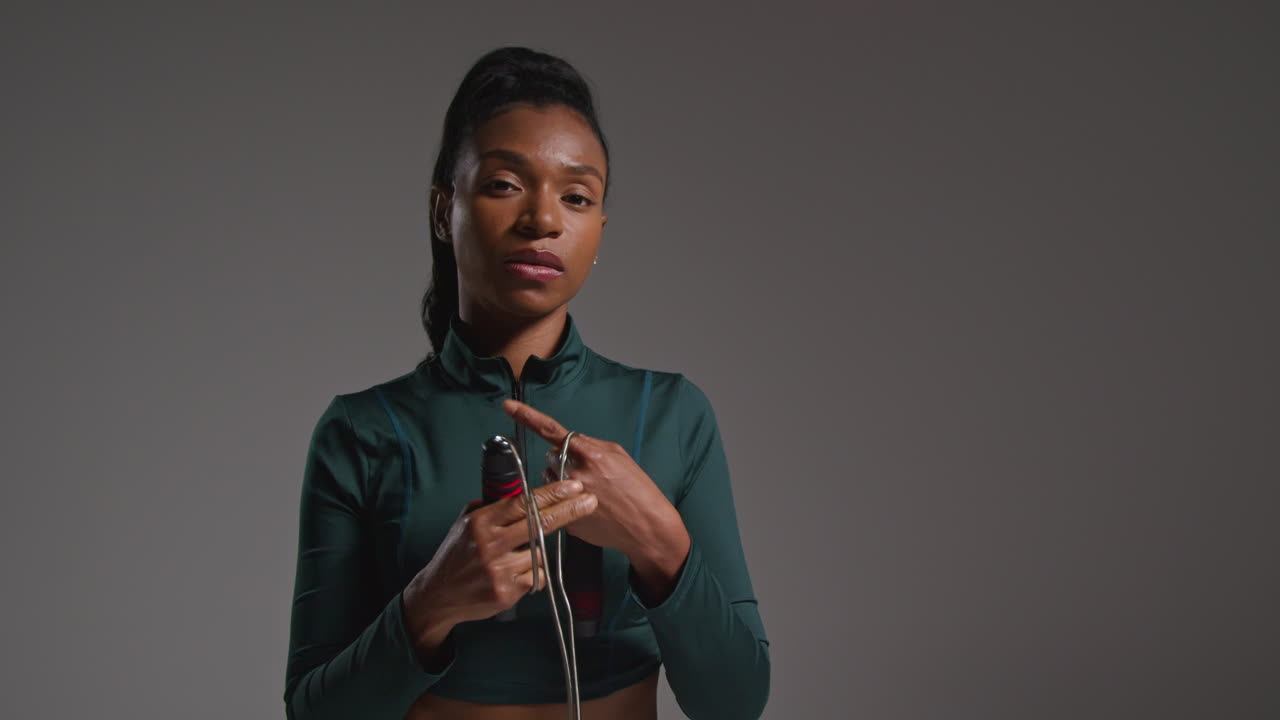 retrato de estudio de una atleta que lleva un traje de entrenamiento en una clase de gimnasia con una cuerda para saltar o una cuerda de salto contra un fondo plano 1