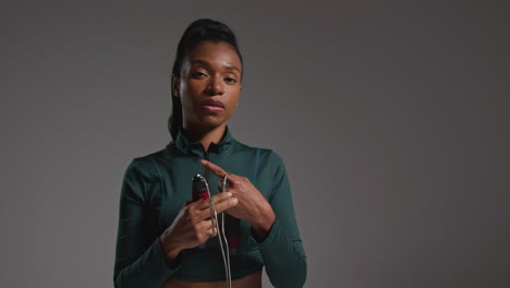 Studio-Portrait-Of-Female-Athlete-Wearing-Tracksuit-Training-In-Gym-Fitness-Class-With-Jump-Rope-Or-Skipping-Rope-Against-Plain-Background-1