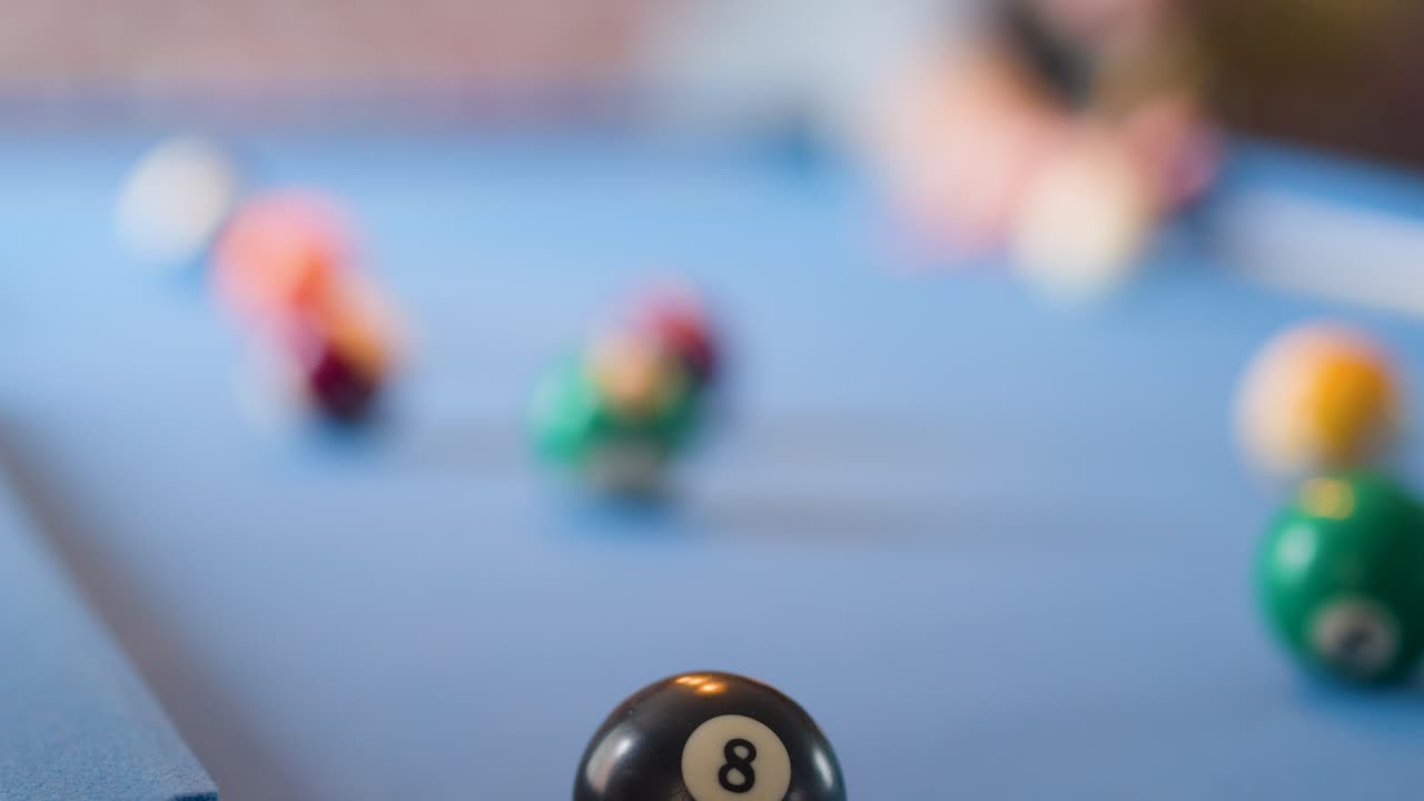 Eight ball is struck and pocketed in close-up, shallow focus, natural lighting, smooth camera tracking