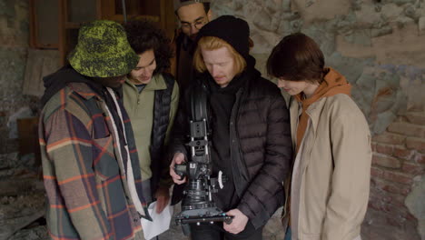 equipo de producción y camarógrafo revisando una escena en una cámara en un edificio en ruinas