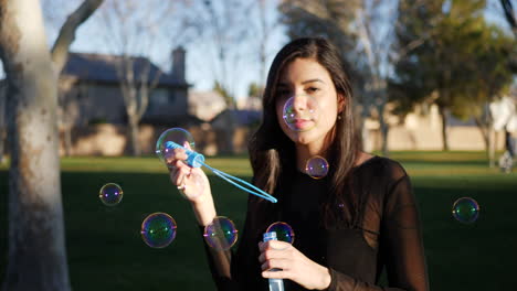una chica hermosa que sopla muchas burbujas de ensueño a la luz del sol mientras sonríe de forma alegre a cámara lenta