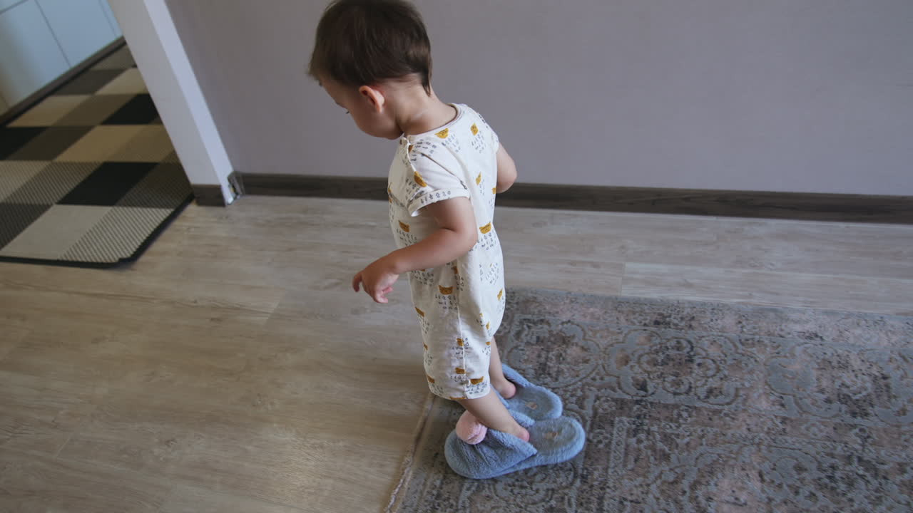 Lovely little kid wearing blue fluffy slippers crosses the room. Kid borrowed his mom's footwear.
