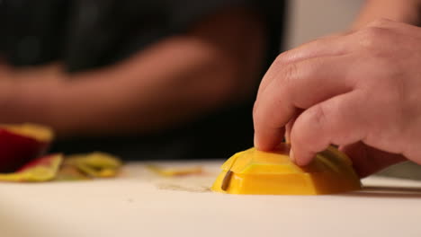 chef slicing ripe mango horizontally using sharp knife at the kitchen