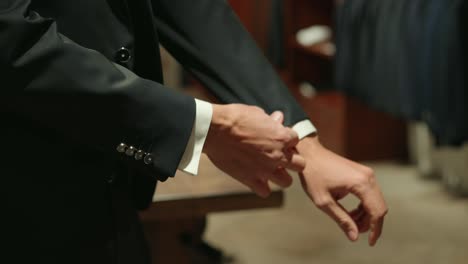 Groom-straightens-sleeves-getting-ready-for-wedding