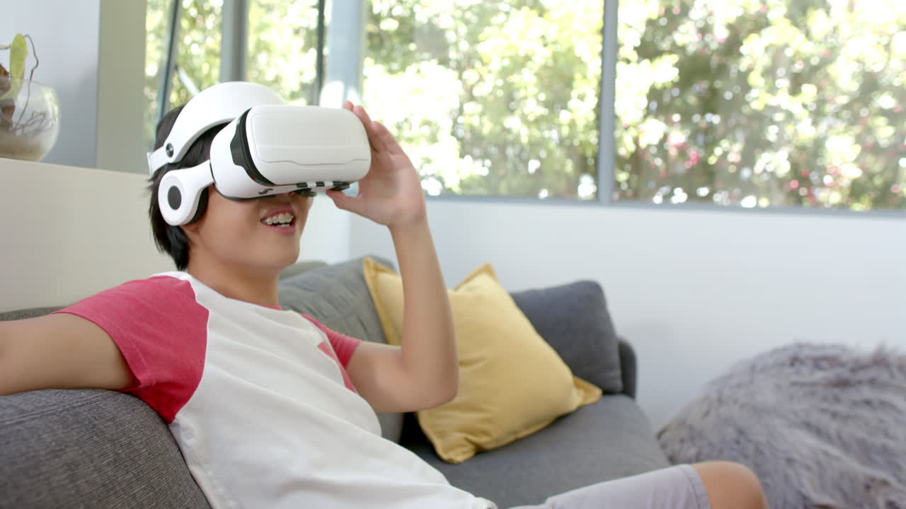 un adolescente asiático disfruta de un auricular de realidad virtual en casa