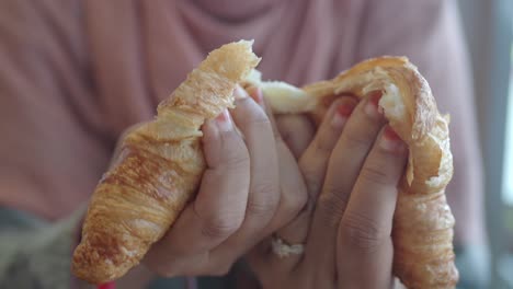 hands breaking a croissant