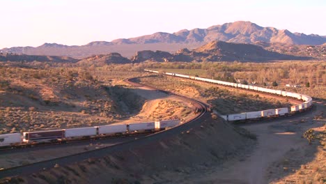 a container freight train moves across the desert from a high angle