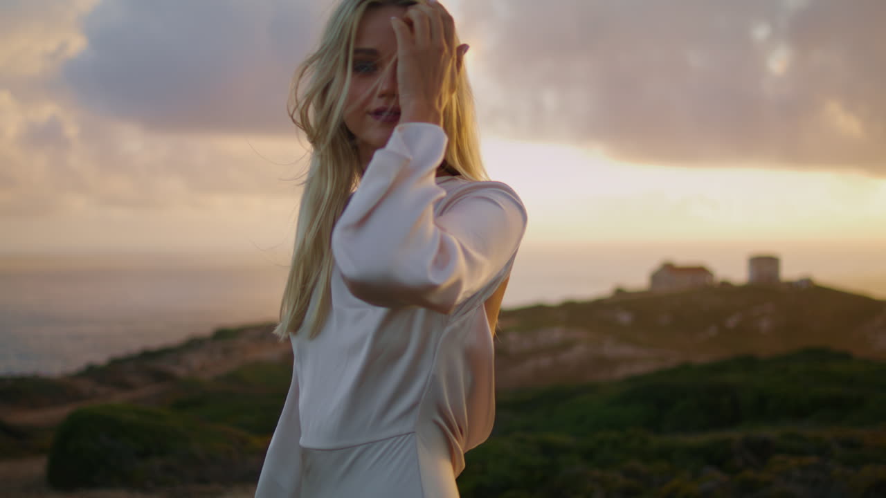 만적 인 모델은 저녁에 자연을 편안하게 확대합니다. 긍정적 인 여성은 머리카락을 만니다.