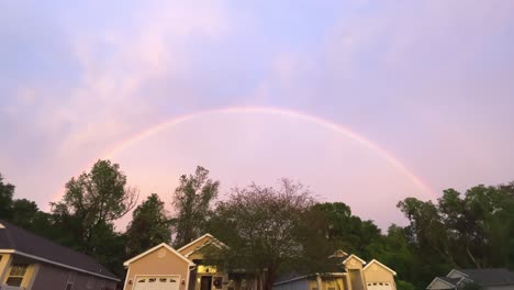 full rainbow over houses at sunset