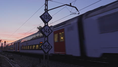 speed passenger train passes on railroad track during sunset nightfall