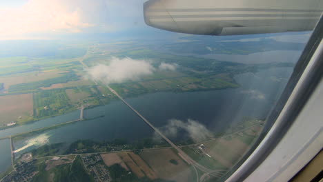 through airplane window view, aircraft, plane window, aerial sky, clouds, river view, during flight plane seat view looking through the window