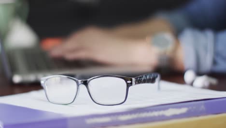 biracial woman working at home with laptop and glasses on table in slow motion