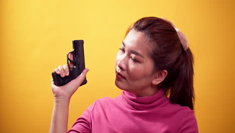 series asian woman with a handgun ready to self-defense on bright yellow background