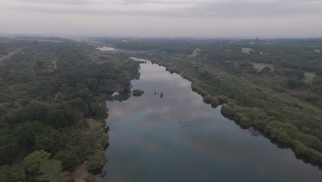 drone descends or dips low over the seasonal komati river, revealing the vastness of the bushveld awakening