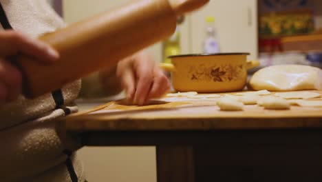 hands of grandmother rolling dough for dumplings on wooden board