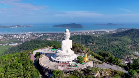 drone footage captures the serene big buddha statue overlooking lush landscapes and the andaman sea in phuket, thailand