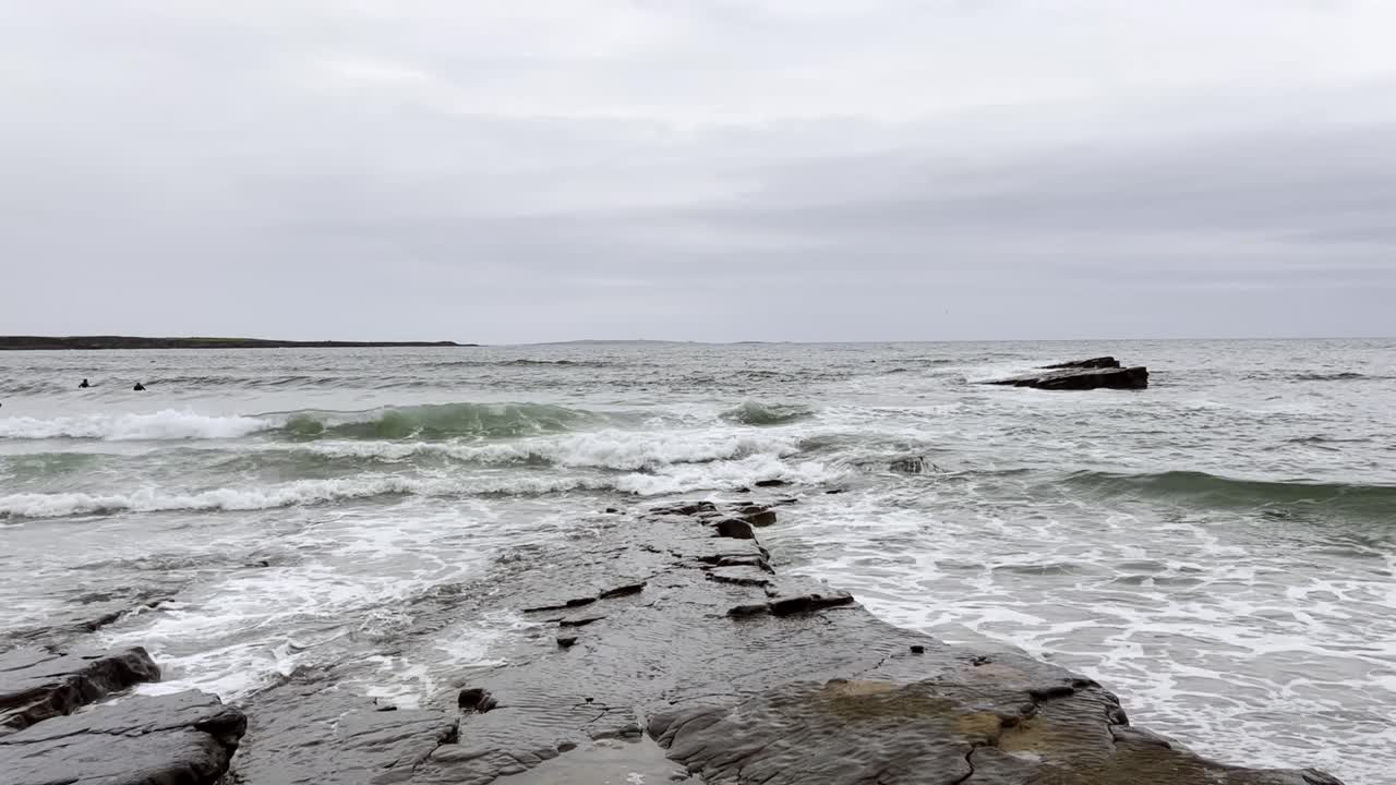 olas en la playa punto español en irlanda - olas golpean rocas en la costa - surfistas esperando olas